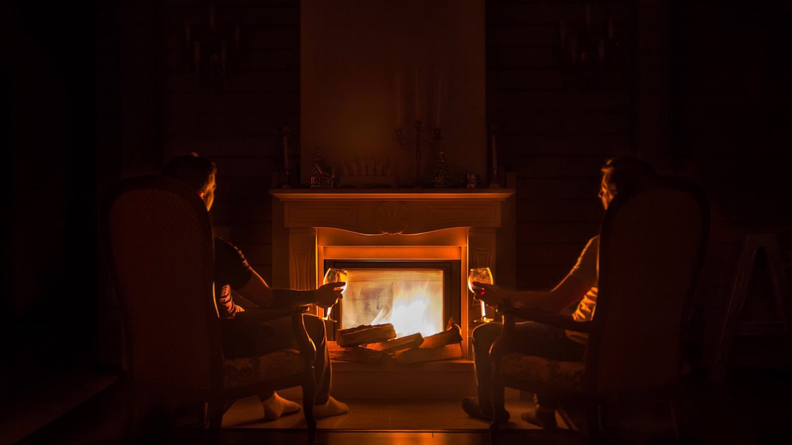Two armchairs beside a lit fireplace