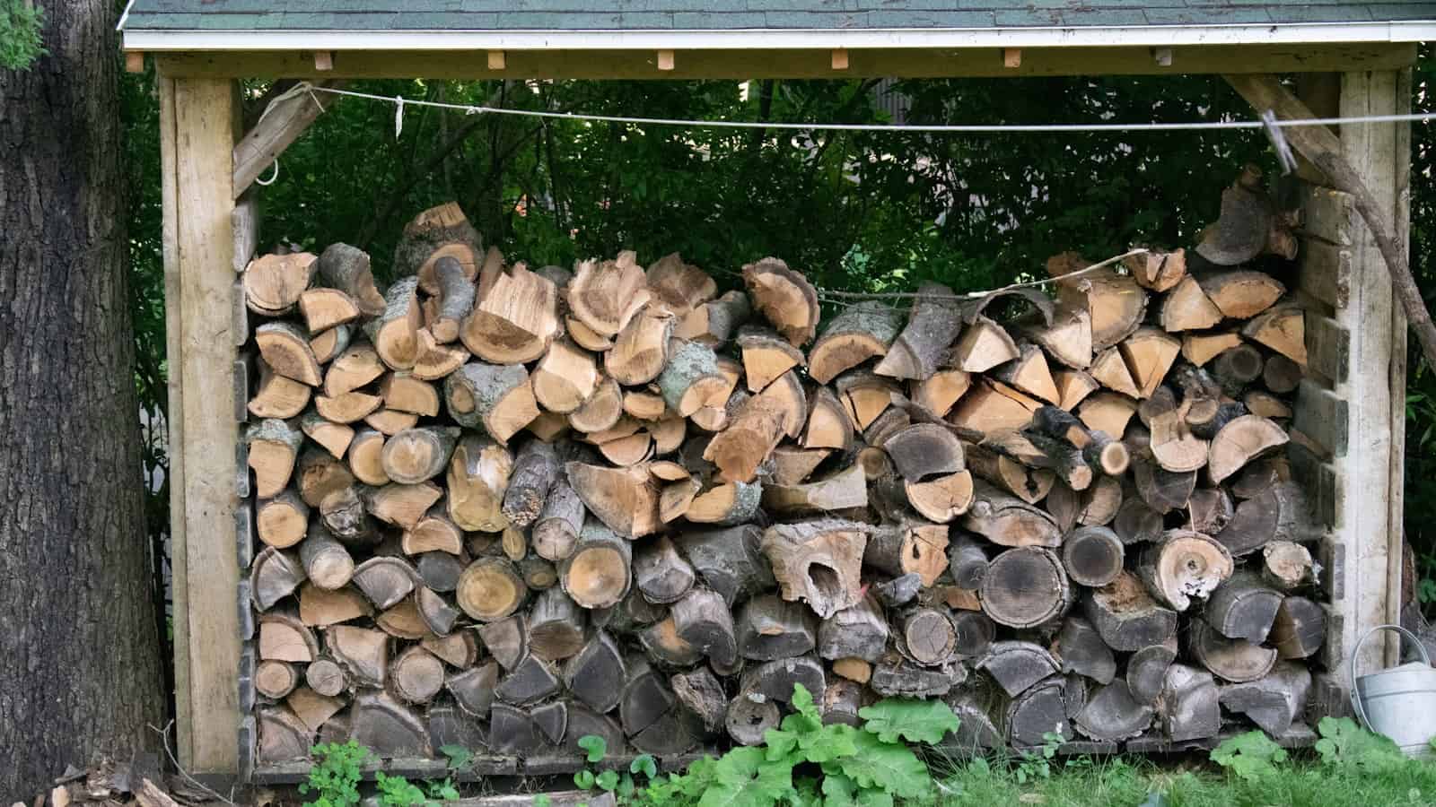 Firewood stacked under a roof, off the ground and open at the sides