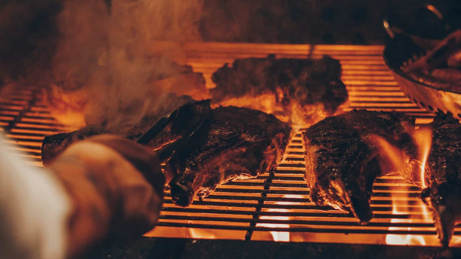 Steaks searing over restaurant charcoal